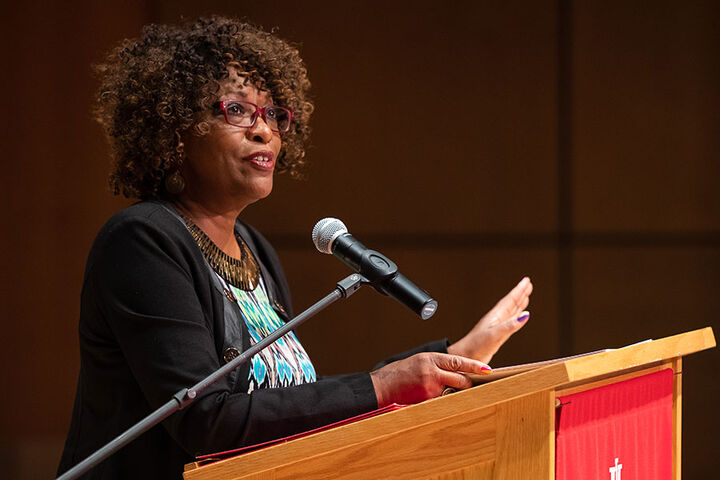 A faculty scholar stands at a podium in a lecture hall.